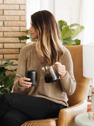 Naine beežis kampsunis, kellel on barista espresso serveerimiskann klaasist, kaasaegne disain, Viimased uudised, kõik kohvi kohta.